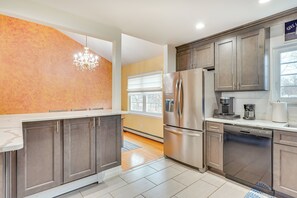 A modern kitchen with stainless steel appliances, wooden cabinets, and a large window providing natural light. - 4 Mi to Hudson River: Cozy Newburgh Home! (Newburgh)