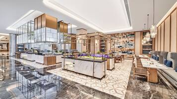 A modern hotel lobby with a central bar area, seating arrangements, and a patterned floor.