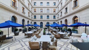 A spacious outdoor patio with multiple tables and chairs, blue umbrellas, and potted plants. - TUI BLUE Taicang Hotel (Suzhou)