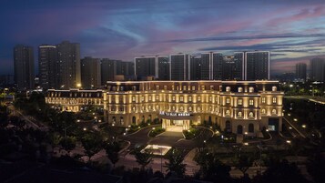 Un hotel grande de varios pisos con un diseño arquitectónico clásico, que cuenta con un patio central e iluminación exterior.