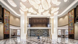 A spacious lobby with a high ceiling, large columns, and a central decorative wall. - TUI BLUE Taicang Hotel (Suzhou)