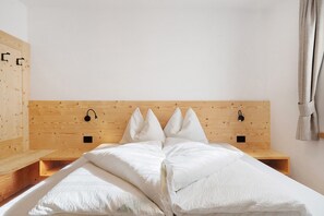 Un dormitorio con cabecera de madera, ropa de cama blanca y una mesita de noche pequeña.