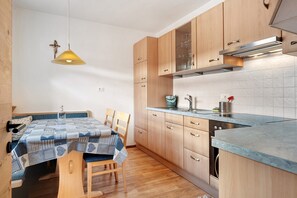 Una cocina moderna con armarios de madera, horno empotrado y un comedor con mesa y sillas.