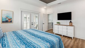 A bedroom with a bed, a TV, a dresser, and a door. - Private Hot Tub| Community Pool| Boat Docks| Perdido Beaches| Yard Games| Close to NAS| Free Golf (Pensacola)