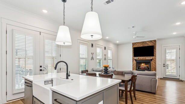 A modern kitchen with a central island, a dining area with a sofa, and a fireplace. - Private Hot Tub| Community Pool| Boat Docks| Perdido Beaches| Yard Games| Close to NAS| Free Golf (Pensacola)