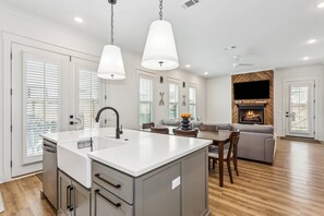 Una cocina moderna con una isla central, un área de comedor con sofá y una chimenea.