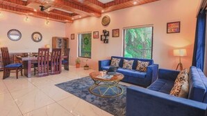 Una sala de estar con un sofá azul, una mesa de centro y un comedor con sillas y una mesa.