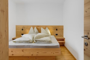 Un lit bien fait, avec une tête de lit en bois, une table de chevet et un luminaire fixé au mur.