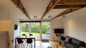 A modern kitchen with a dining area, a sofa, and a TV. - Pretty Bungalow in Sint Maartenszee (Sint Maartensvlotbrug)