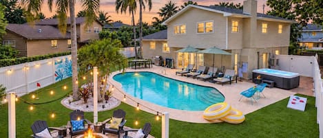 Un patio trasero con piscina, mobiliario de exterior y bañera de hidromasaje.