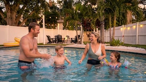 A swimming pool with inflatable rings, a white fence, and outdoor seating. - 4 Minutes to Beach | Pool | Hot Tub | Game Room (Seminole)