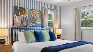 A neatly made bed with a blue headboard, two bedside lamps, and a window with curtains. - 4 Minutes to Beach | Pool | Hot Tub | Game Room (Seminole)