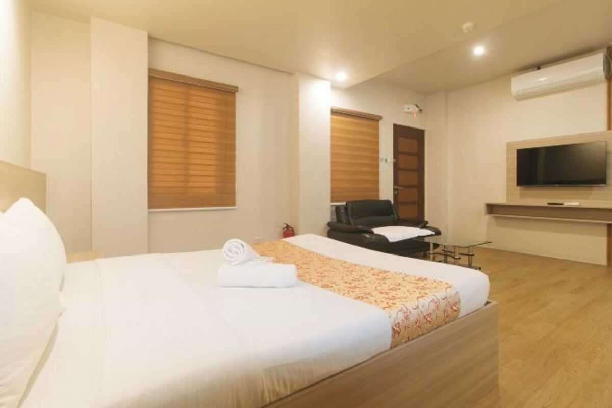 A hotel room with a bed, a TV, a chair, and a desk.