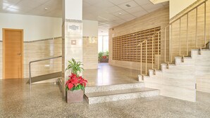 A modern lobby with a marble floor, a staircase with wooden railings, and a potted plant. - Apartment 'Centro Internacional A117' with Sea View, Wi-Fi and Air Conditioning (Torrox)