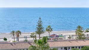 A coastal view with a beach, palm trees, and a building with a tiled roof. - Apartment 'Centro Internacional A117' with Sea View, Wi-Fi and Air Conditioning (Torrox)