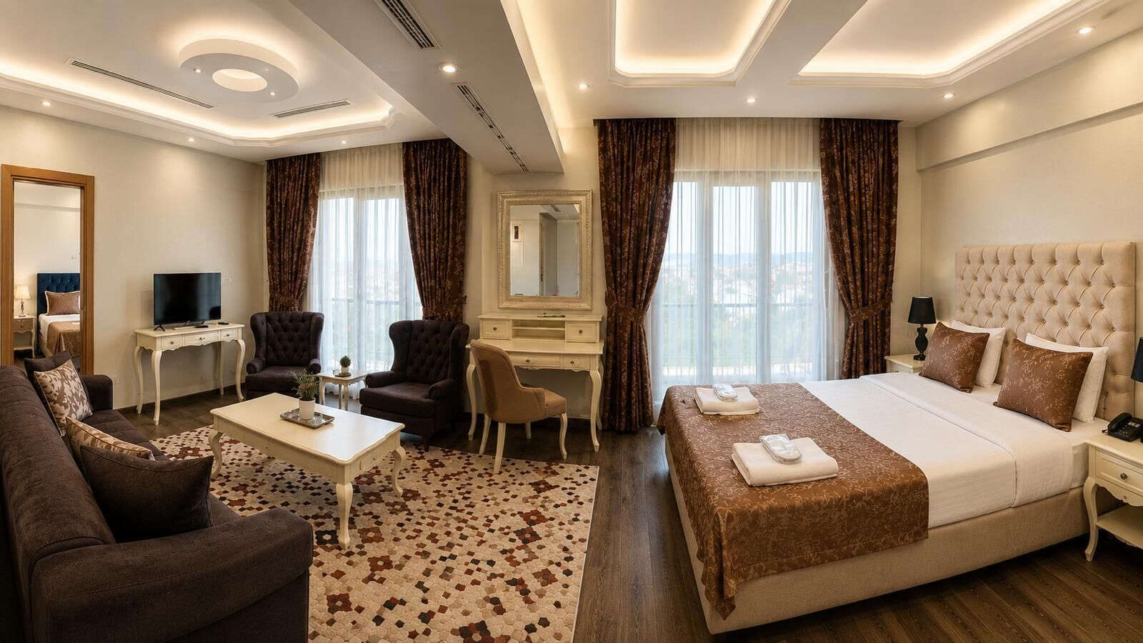 Habitación de hotel con cama, escritorio, silla, sofá, televisor y espejo.