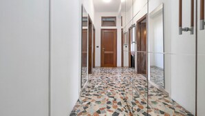 A hallway with a tiled floor, wooden doors, and a mirror on the wall. - Family Comfort Sole Apartment with Balcony, Wi-Fi and Air Conditioning (Cagliari)