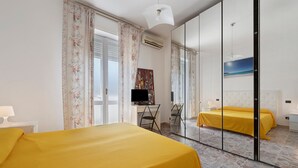 A hotel room with a bed, a desk, a chair, a mirror, and a painting on the wall. - Family Comfort Sole Apartment with Balcony, Wi-Fi and Air Conditioning (Cagliari)