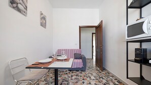 A compact kitchen with a dining table set for two, a microwave, and a small refrigerator. - Family Comfort Sole Apartment with Balcony, Wi-Fi and Air Conditioning (Cagliari)