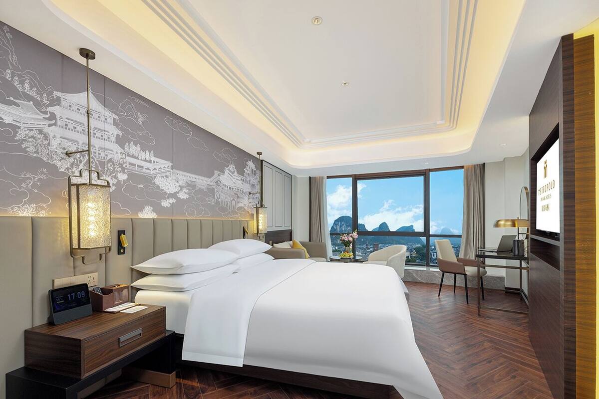 Ein modernes Hotelzimmer mit einem großen Bett, einem Schreibtisch und Blick auf die Stadt.