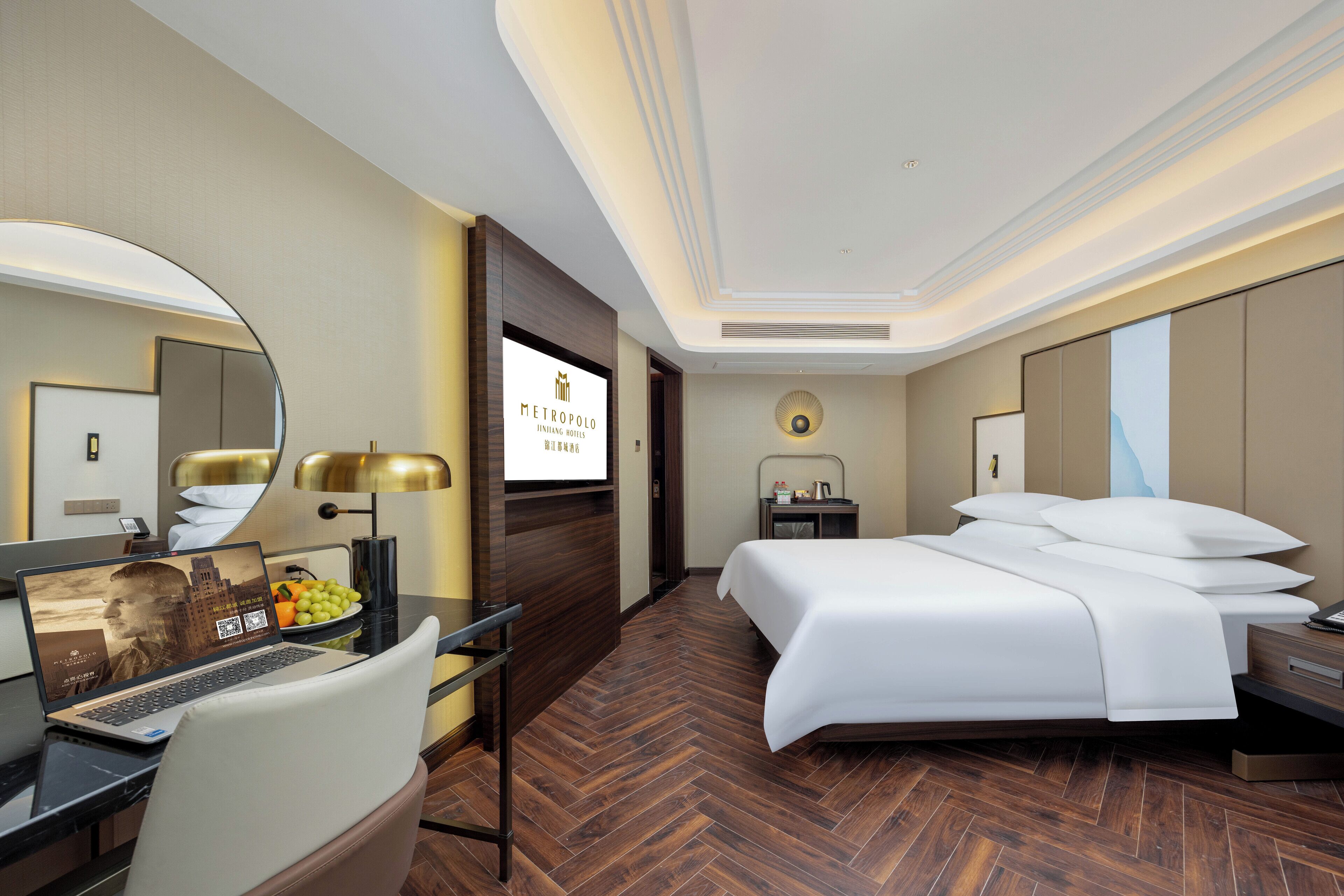 A hotel room with a bed, desk, chair, and a large mirror.