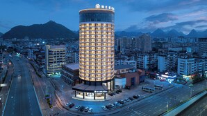 Un hotel moderno de diseño cilíndrico, rodeado por un paisaje urbano y montañas al fondo.