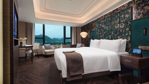 Habitación de hotel con una cama grande, un escritorio y vistas a las montañas.