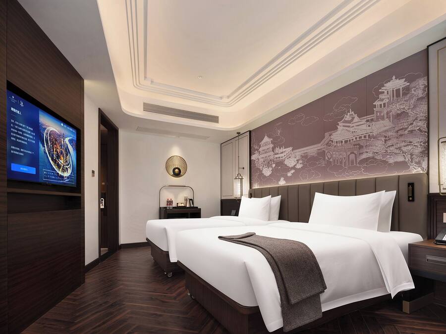 Quarto de hotel com uma cama grande, televisão na parede e um painel decorativo.