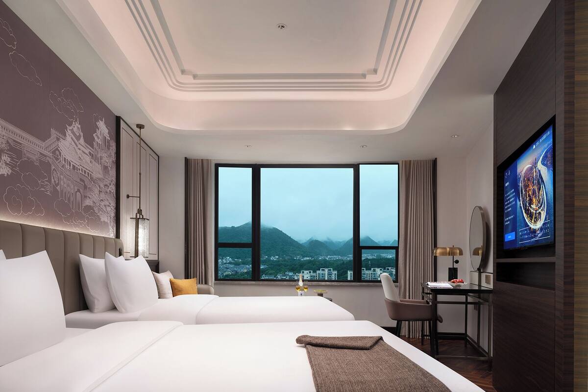 Ein modernes Hotelzimmer mit einem großen Bett, einem Schreibtisch und einem Fernseher.