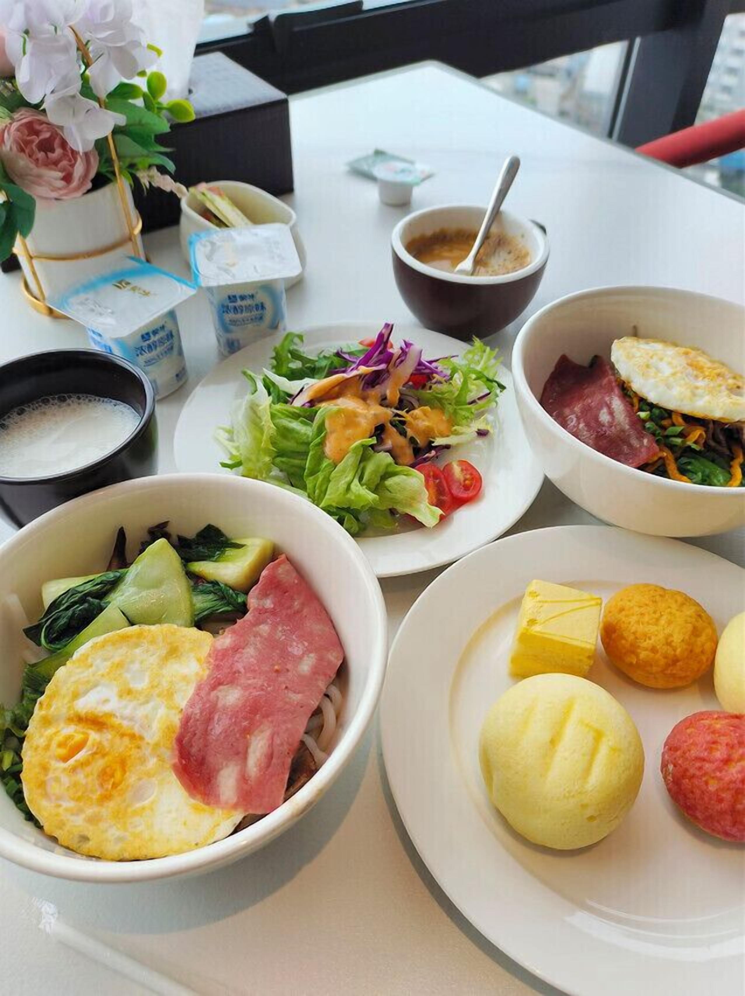 A table with various dishes including a salad, soup, and a plate with dumplings and meat.