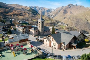 A village with traditional architecture, a playground, and a mountain backdrop.