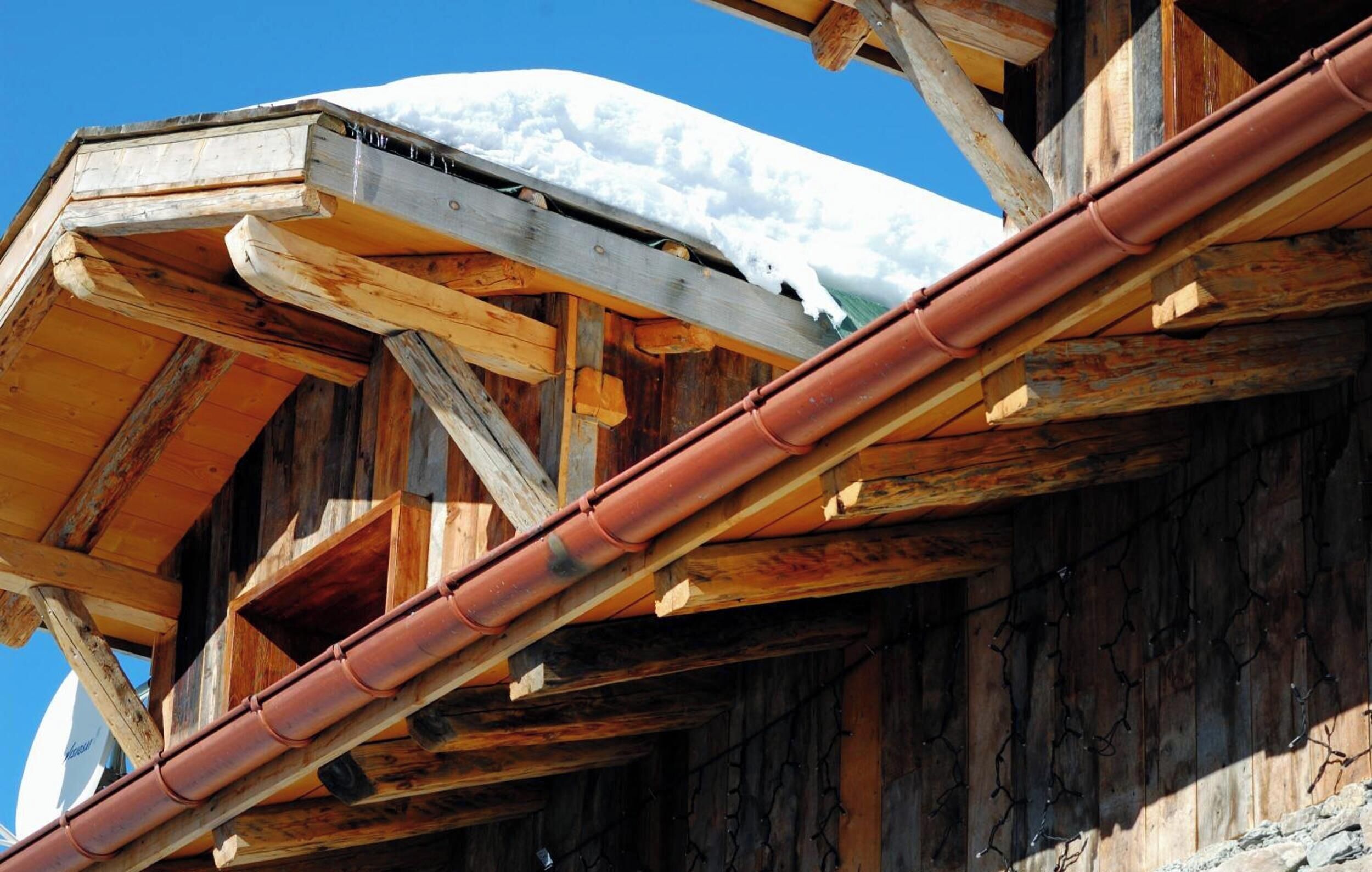 A wooden structure with a snow-covered roof and a visible metal gutter.