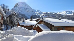 A snow-covered mountain village with wooden buildings, a ski lift, and a clear blue sky. - Chalet La Corniche, cozy for 13, sauna with mountain views and private terrace (Les Belleville)