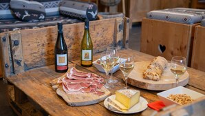 A wooden table with a bottle of wine, glasses, a cheese plate, a meat platter, and a bread roll. - Chalet La Corniche, cozy for 13, sauna with mountain views and private terrace (Les Belleville)