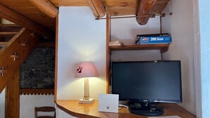 Ett skrivbord i trä med en datorskärm, en lampa och en låda märkt med texten ”200 Jeux”.