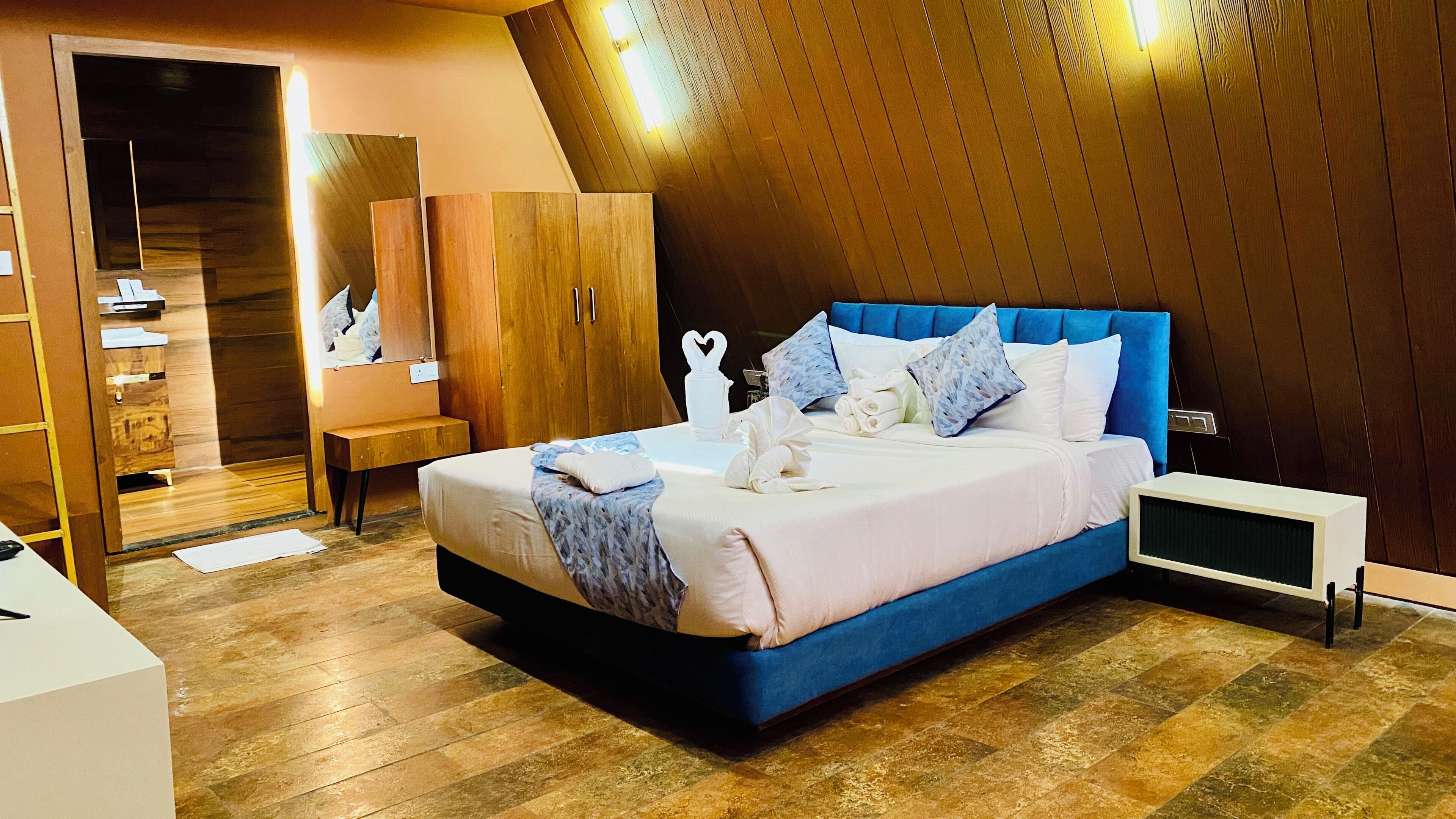 Une chambre à coucher moderne avec un grand lit, une armoire en bois et un miroir.