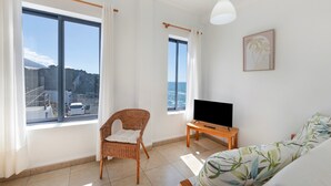 A room with a large window, a television, a wicker chair, and a sofa. - Apartment 'La Bayana - 6' with Sea View, Shared Pool and Wi-Fi (Los Llanos)