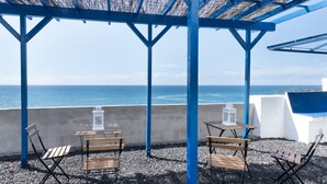 An outdoor seating area with tables and chairs, overlooking the sea. - Apartment 'La Bayana - 6' with Sea View, Shared Pool and Wi-Fi (Los Llanos)