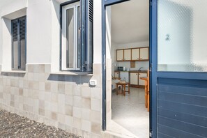 Una propiedad residencial con fachada de baldosas, una puerta corrediza de vidrio que da a una cocina con armarios de madera y un comedor.