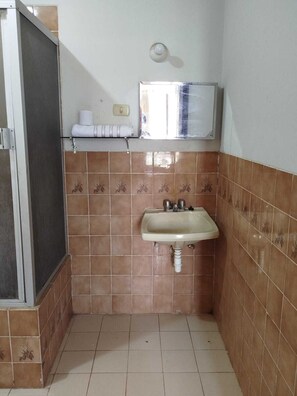 Un baño pequeño con lavamanos, inodoro y ducha.