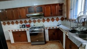 Una cucina compatta con mobili in legno, un fornello a gas e un forno integrato.