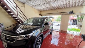 Un SUV nero parcheggiato in un garage con pavimento piastrellato e una scala.