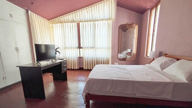Una camera da letto con un letto, una scrivania, un armadio e una finestra con tende.