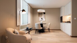 A modern living room with a sofa, a dining table with chairs, a pendant light, and a kitchen area with cabinets and appliances. - Stella Braga Aparthotel (Braga)