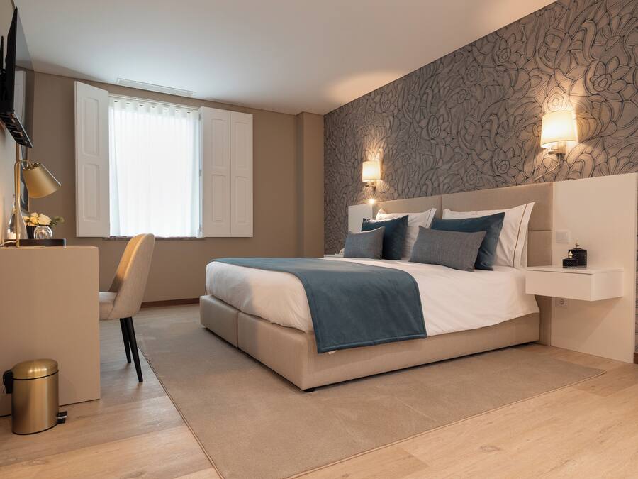 A modern bedroom with a bed, bedside tables, a desk, and a chair.