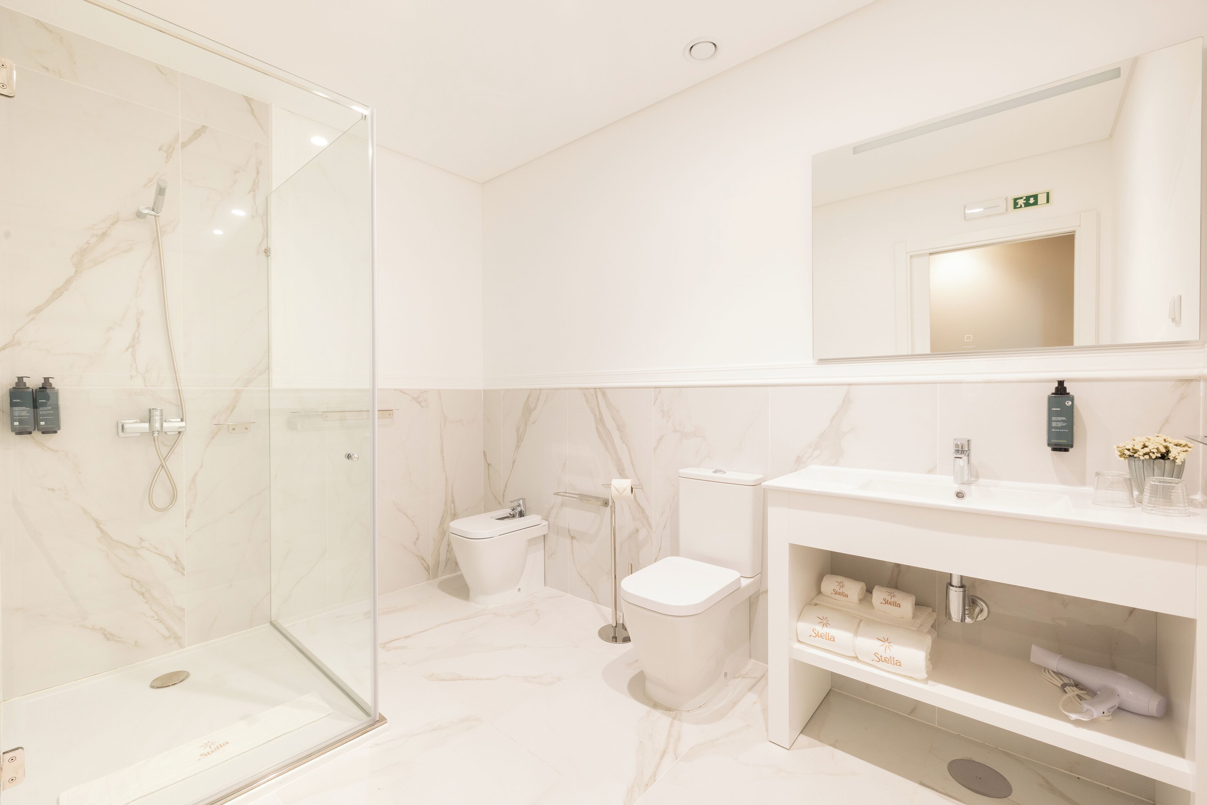 Une salle de bain moderne avec une douche à parois de verre, des toilettes et un meuble-lavabo avec des articles de toilette.
