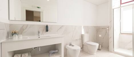 A modern bathroom with a white vanity, a mirror, a toilet, and a shower area.
