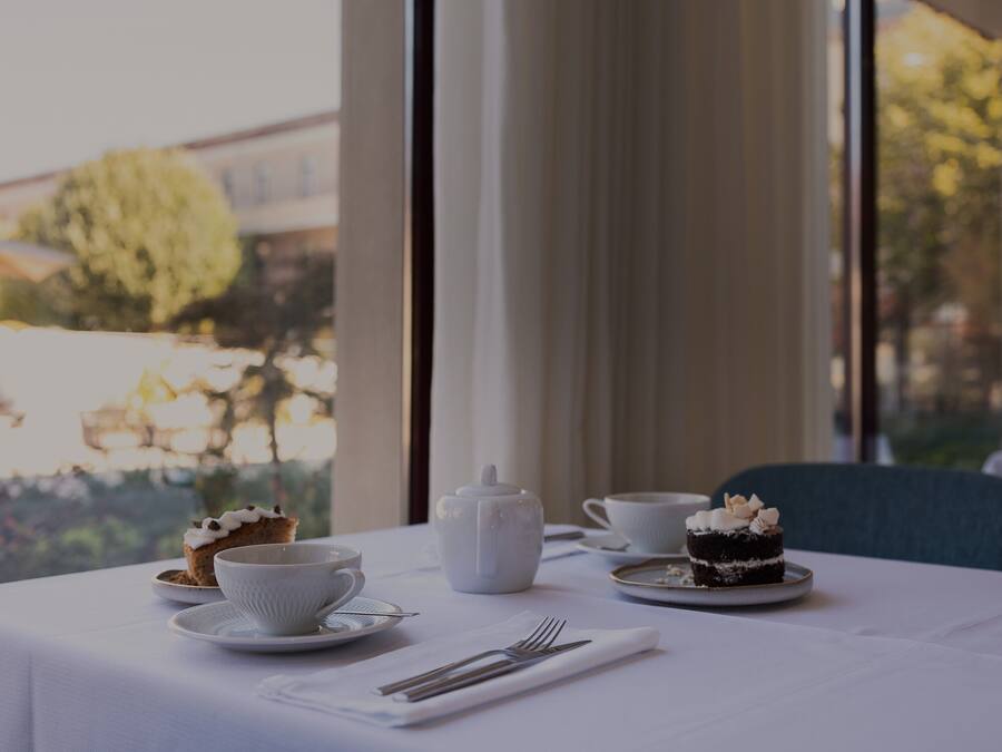 A table set for tea with a teapot, cups, and a cake.