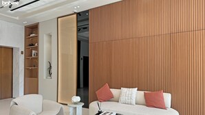 Un vestíbulo moderno de hotel con un sofá, un sillón y una pequeña mesa con un libro y un jarrón de flores.