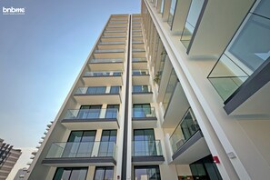 A multi-story hotel with a modern architectural design, featuring balconies and large windows. - bnbme - Binghatti Lavender - STUDIO (Dubai)
